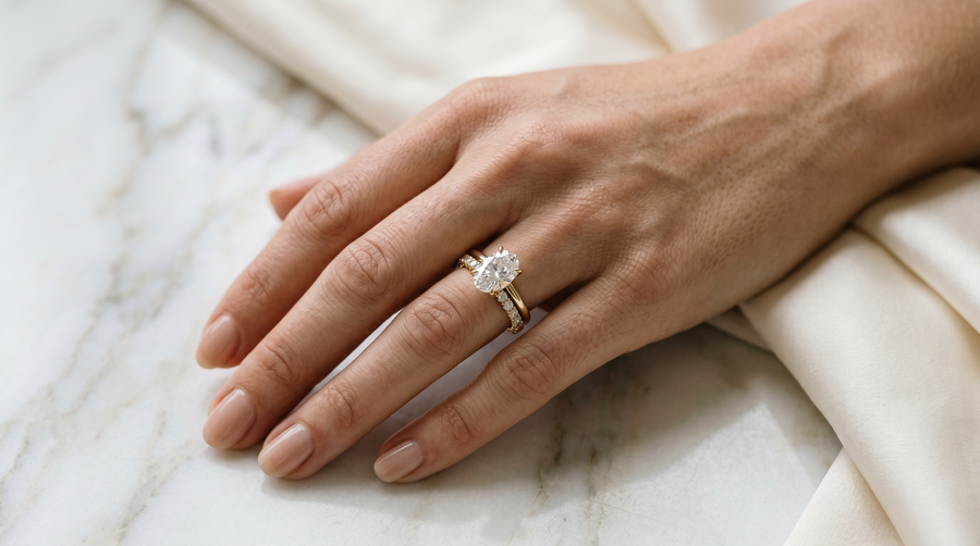 Lab grown diamond bridal set on hand - oval engagement ring and half-eternity wedding band in 14k yellow gold sitting flush